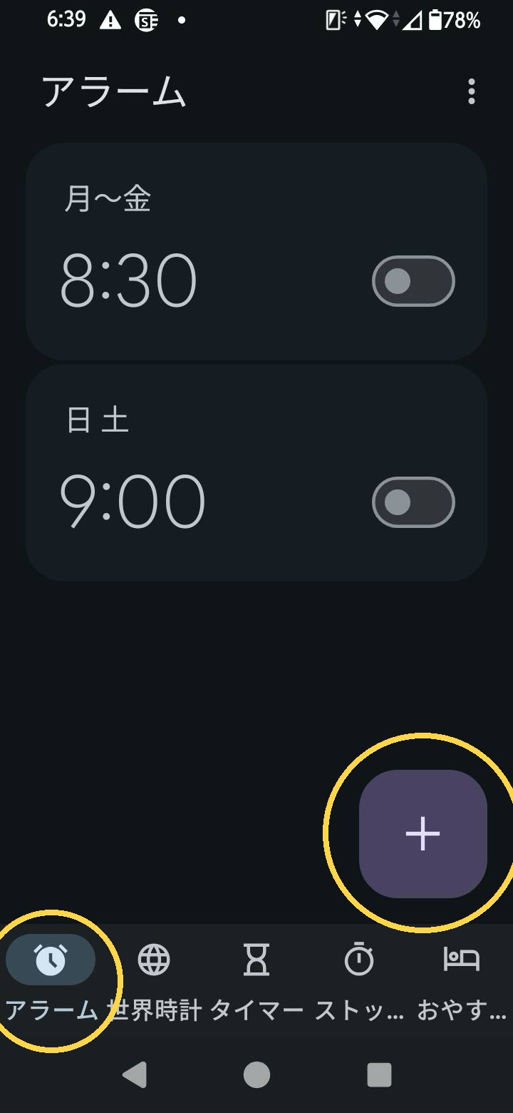 Androidの時計アプリ、アラーム一覧画面。下部の時計マークのアラームタブと右下の+ボタンを黄色い丸で囲んで示している