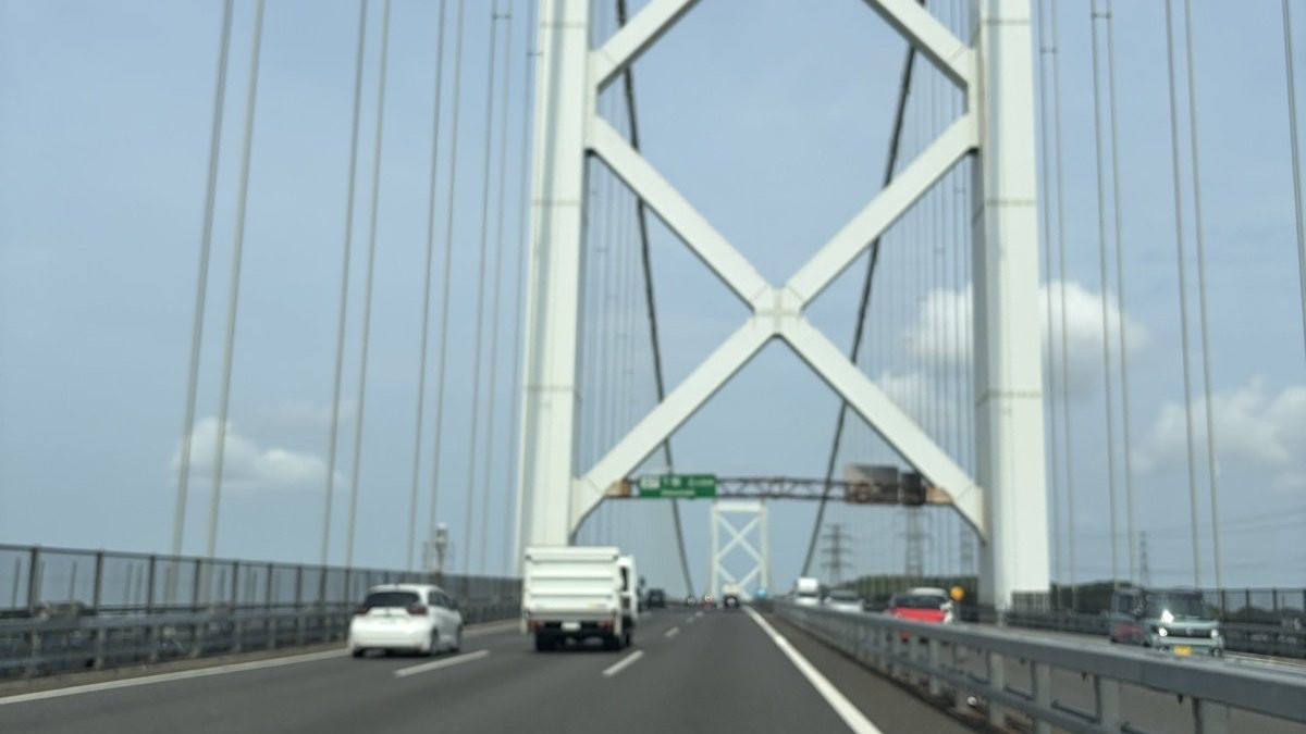 日中に関門橋を通過する様子。橋の主塔の白い鉄骨と、周囲を走る他の車が写っている