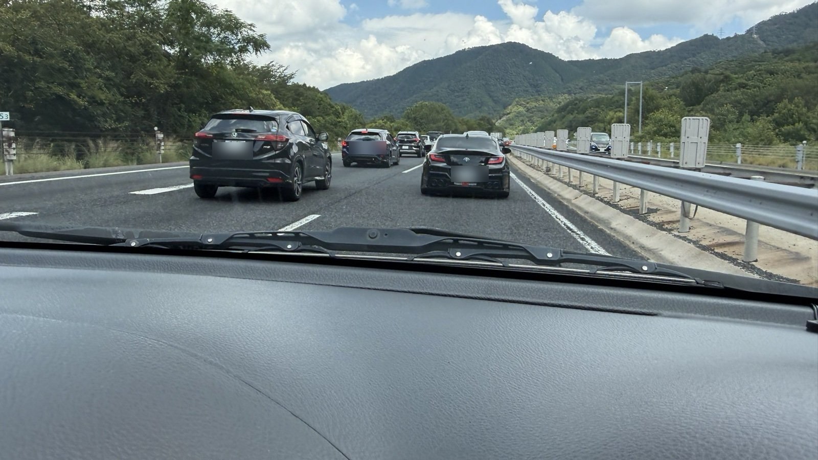山あいの高速道路で複数台の車が連なって渋滞している様子(ナンバープレートはぼかし済み)