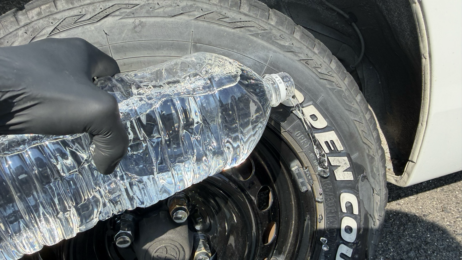ペットボトルの水をホワイトレターにかけている場面