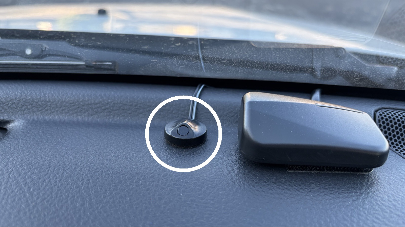 運転席のダッシュボード上にある、白い丸で囲んだ小さな丸い黒い部品が、オートライトのセンサー。右隣の黒い四角い箱は別の機器